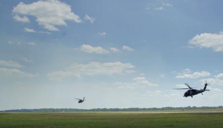 military helicopters flying above agriculture field