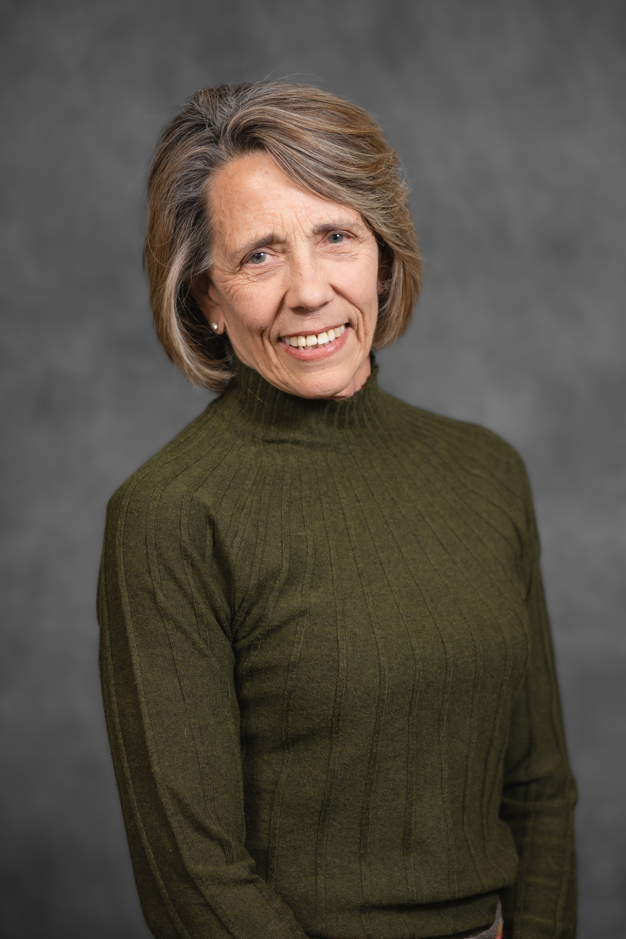 Image of a woman smiling in front of a grey backdrop 