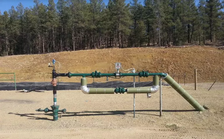 oil and gas injection well which depicts several pipes protruding from a dirt pad